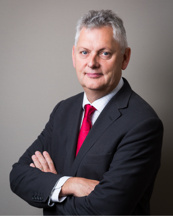 Dr Mark Downs looking towards camera with arms folded